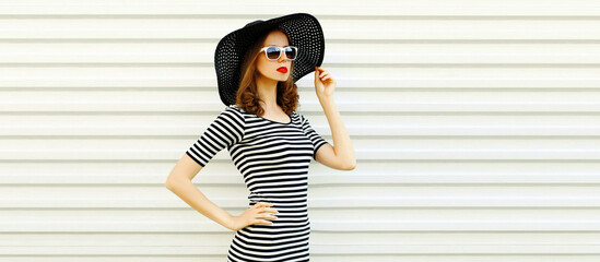 Portrait of beautiful woman model wearing black round summer hat, striped dress on white background