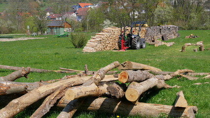 Fototapeta premium Traktor mit Holzspalter, Langholz und Brennholz