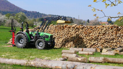 Traktor mit Holzspalter vor einem Stapel Holz © turtles2