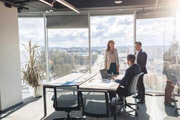 Team of young businessmen working and communicating together in modern office with panoramic...