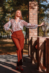 The girl is a model showing fashionable outerwear on the street, on the veranda of a summer cafe. Clothes for the showroom