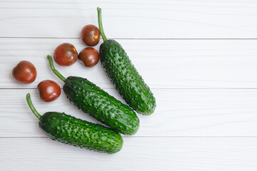 Fresh cucumbers and cherry tomatoes on light wooden boards. Vegetables from a constant diet, organic cucumber and tomatoes from a greenhouse. Top view, copy space