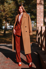 The girl is a model showing fashionable outerwear on the street, on the veranda of a summer cafe. Clothes for the showroom