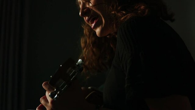 Mujer tocando el ukulele y cantando en su habitaci&oacute;n. Concepto de musica.