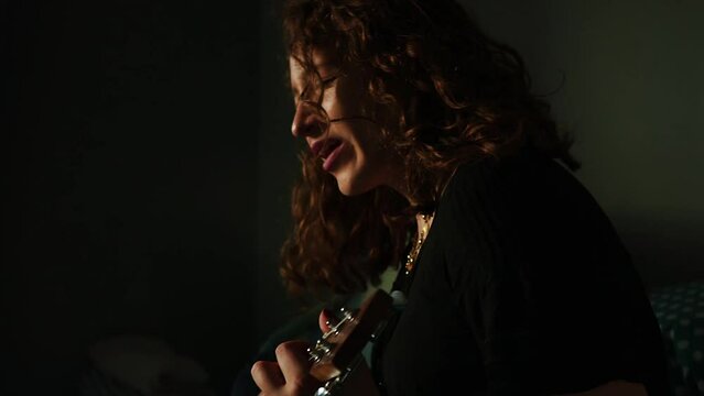 Mujer tocando el ukulele y cantando en su habitaci&oacute;n. Concepto de musica.