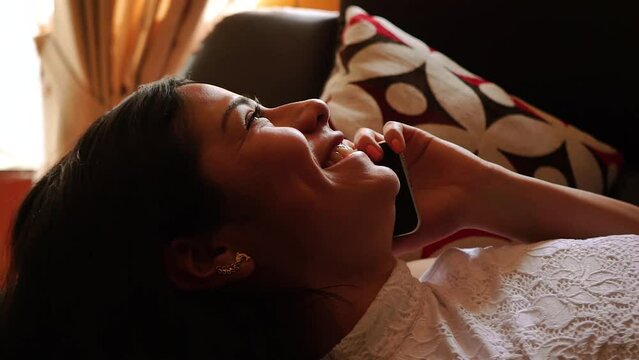Mujer habla por tel&eacute;fono sonriente en su casa. Concepto de hogar y tecnolog&iacute;a.