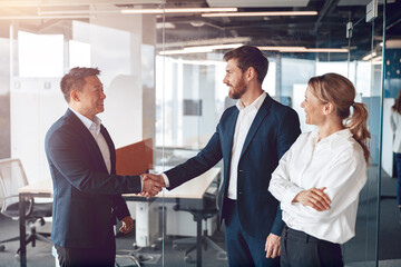 Welcome to our team, mature modern men in formal wear shaking hands in modern office.