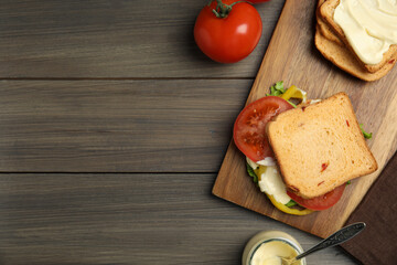 Delicious sandwich with vegetables and mayonnaise served on wooden table, flat lay. Space for text