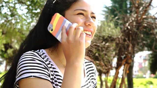Mujer conversando por tel&eacute;fono muy contenta en un parque. Concepto de tecnolog&iacute;a