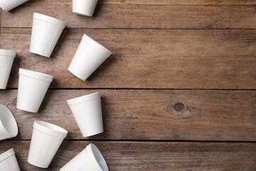 Many white styrofoam cups on wooden table, flat lay. Space for text
