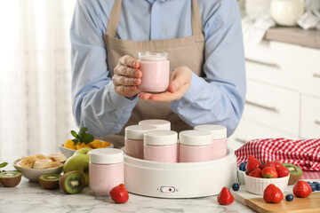 Woman making tasty yogurt at white marble table in kitchen, closeup