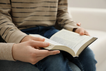 Boy and his godparent reading Bible together indoors, closeup