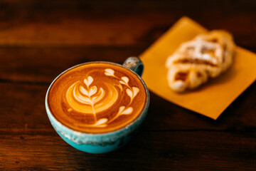 cup of coffee with latte art and breakfast on wood table.
