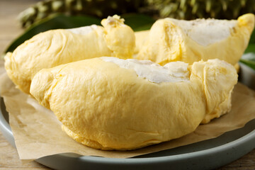 Plate with fresh ripe durian on wooden table, closeup