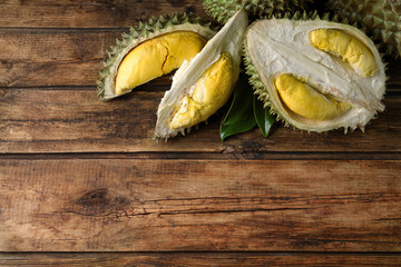 Fresh ripe durian fruits on wooden table, flat lay. Space for text