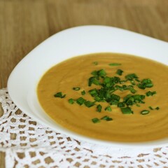 Zdrowa zupa krem w kolorze pomarańczowym posypana zieleniną