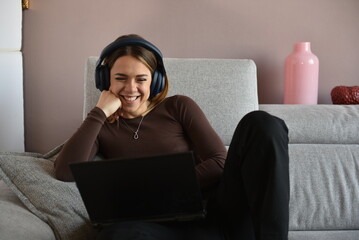 bellissima ragazza sorridente che guarda il monitor del computer seduta sul divano