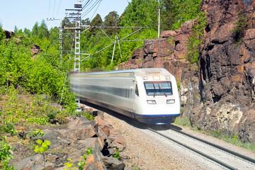 High-speed electric train rushes through a canyon in a mountainous rocky area.