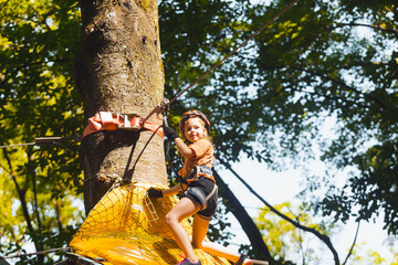The concentrated girl carefully overcomes obstacles in the rope park