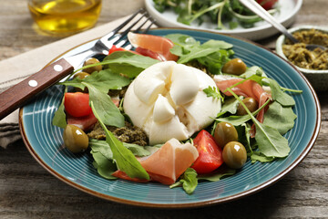 Delicious burrata salad served on wooden table, closeup