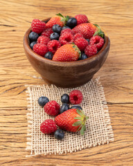 Strawberries, blueberries and raspberries in a bowl over wooden table