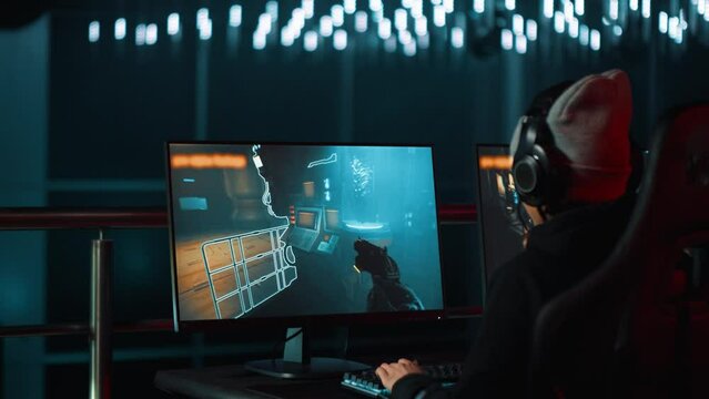 Professional female gamer plays shooter video game with special effects on computer at championship event.