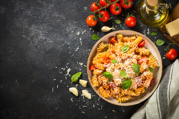 Italian pasta alla arrabiata with fresh tomatoes, basil and parmesan on black stone table. Top view with copy space.