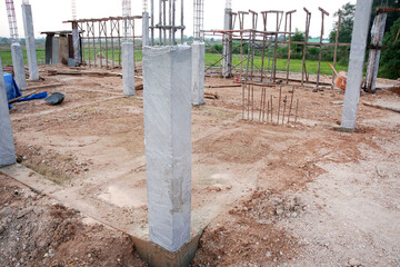 Fototapeta na wymiar Concrete columns at the construction site are covered with plastic. Concrete curing method.