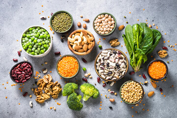 Obraz na płótnie Canvas Vegan protein source. Legumes, beans, lentils, nuts, broccoli, spinach and seeds. Plant based food. Top view on gray stone table.