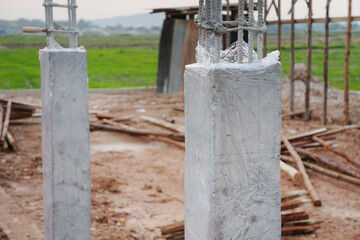 Concrete columns at the construction site are covered with plastic. Concrete curing method.
