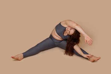 Concentrate curly haired, corpulency barefoot woman doing sports gymnastics incline with arms to...