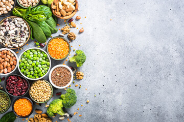 Vegan protein source. Legumes, beans, lentils, nuts, broccoli, spinach and seeds. Top view with copy space at gray stone table. Healthy vegetarian food.