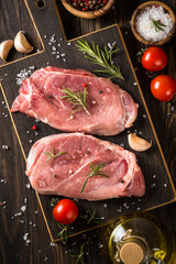 Raw meat. Fresh steaks with herbs and spices at black background. Top view.