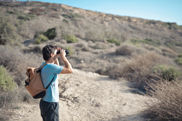 young man looking for target with binoculars