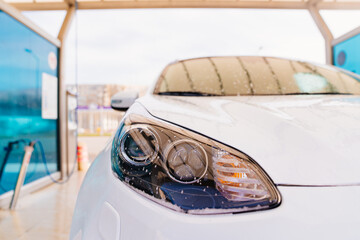 water droplets on the headlight of a white car. self-service car wash. car washer.