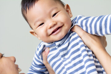 Baby boy smiling and showing his two teeth. Indoors, close up with copy space
