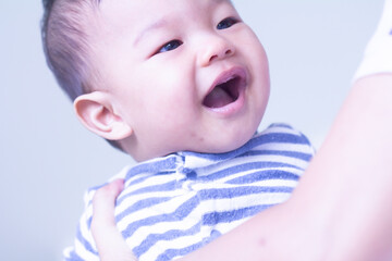 Baby boy smiling and showing his two teeth. Indoors, close up with copy space