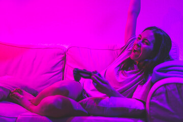young woman at night playing videogames celebrating she is winning