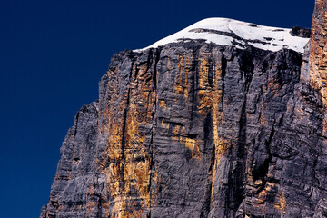Closeup shot of a huge cliff covered in snow against a blue sky