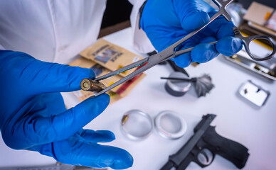 Criminalistic Laboratory, Scientific police officer holds bullet tips with tweezers for ballistic analysis, conceptual image