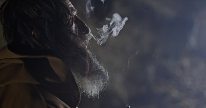 Portrait of an old man with a beard in a medieval cave who actively smokes a vintage pipe in the style of Gandalf from the stories of Tolkien