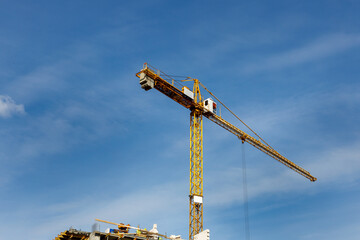 Żółty dźwig na niebie w słoneczny dzień w trakcie budowy budynków mieszkalnych. © Clear Emotion