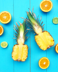 Vertical shot of cut pineapples and citruses on a blue wooden surface