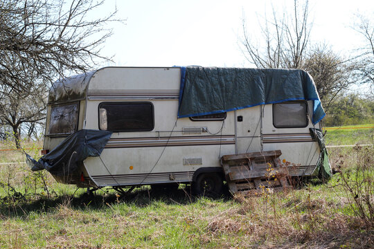 An abandoned caravan stands in a meadow and decays