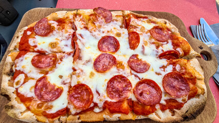 Pizza Salami in romana style, a classic dish from Italy. Eating lunch in a restaurant in the city center of  Padua, Veneto, Italy, Europe.  Tomato, cheese, and spicy salami. Vacation concept