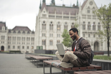 young man sitting on a bench uses a computer © olly