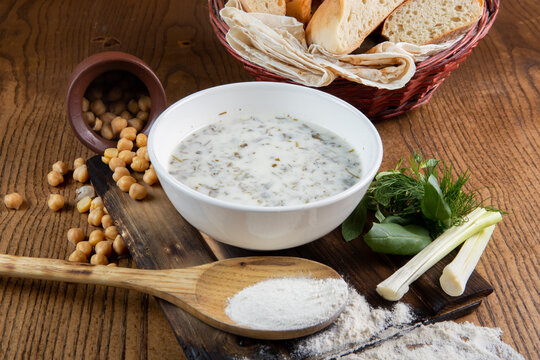 View Of A Milk Soup Or Porridge With Beans Spilling From A Pot And Bread On A Wooden Table