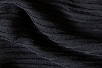 Black wavy fabric as background close up, textile and fashion