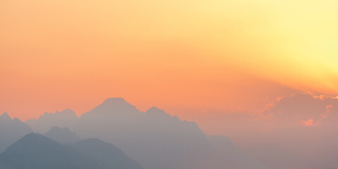 Fototapeta na wymiar bright sunset or sunrise sky with misty mountains