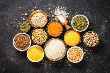Gluten free cereals. Different bowls with rice, buckwheat, corn, lentils, soy beans and quinoa at black. Allergen free food. Top view with copy space.